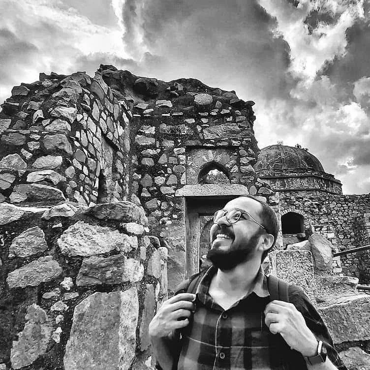 K V Ketan smiling at an old stone fort